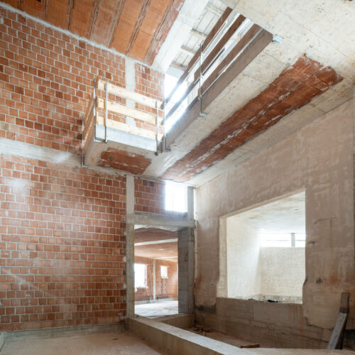 Complesso residenziale contemporaneo con facciate in calcestruzzo a vista, attici in XLAM e hall a doppia altezza